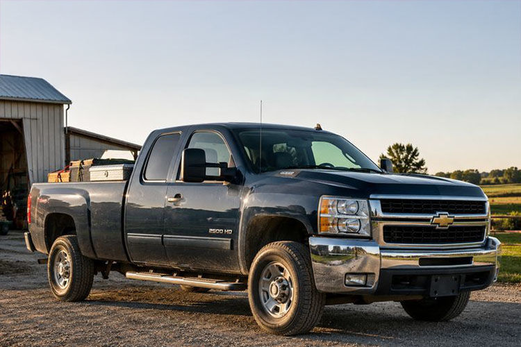 Photorealistic image of used full-size pickup trucks on an active job site with tools and materials in the truck beds, highlighting durable trucks used for hauling and construction work.